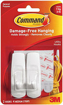 A 2-pack of white plastic medium utility hooks from the Command brand, packaged with four adhesive strips. The package states they hold 3 pounds.