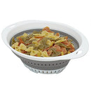 Large, round gray and white collapsible colander filled with colorful pasta.