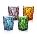 Set of four colored glass tumblers with a faceted design, including blue, purple, green, and yellow, arranged on a white background.
