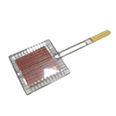 A square metal grilling basket with a long handle and a light wood grip, holding a piece of meat inside.