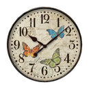 Westclox 12" round wall clock with a cream-colored face featuring three distinct butterfly illustrations in blue, orange, and green. The clock has black numerals, black hour and minute hands, and a black second hand. The background has a subtle vintage paper texture with faint script and stamp-like designs. The clock is encased in a black metal frame.