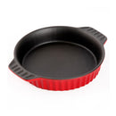 A round, red stoneware casserole dish with a ribbed exterior, a black interior, and two small fluted side handles.