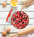 A square, flat, silver stainless steel cake spatula with a wavy, ergonomic red silicone handle on top.