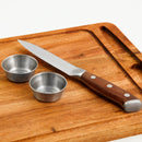 Acacia steak board with knife and two condiment cups displayed on a white background.