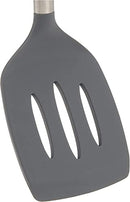 A close-up shot of a dark gray, slotted silicone spatula is presented against a white background. The spatula head is wide and flat with three elongated oval slots arranged vertically. It has a slightly tapered edge, suggesting flexibility. The top part of the image shows a hint of a metallic or stainless steel handle, indicating where the silicone head connects.