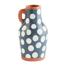 A Mud Pie ceramic vase with a slightly tapered shape, featuring a dark blue glaze with scattered white polka dots. The vase has a small handle on one side and a contrasting terracotta rim and base.