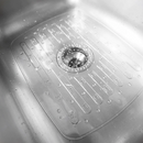 A clear, flexible silicone sink mat with drainage holes and a textured surface, placed in a stainless steel kitchen sink.