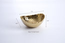 A medium-sized, oval serving bowl with a shiny gold color and a distinctive hammered texture on the entire surface.