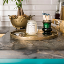 A small, clear glass jar candle with a very light, almost white wax. It has a silver metal lid and a decorative label featuring the scent 'Haven.'