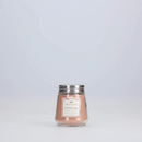 A small, clear glass jar candle with a soft pink/peach colored wax. It has a silver metal lid and a decorative label with the scent "Cashmere Kiss."