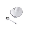 A white ceramic bowl shaped like an apple with a silver rim and stem, accompanied by a white ceramic spoon with silver bands on the handle. Dimensions for the bowl (5" x 4.5" x 2.5") and spoon (5" long) are indicated.