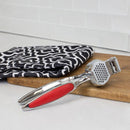 Home Basics Zinc Garlic Press with ergonomic red handles, designed for easy crushing of garlic cloves.