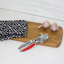 Home Basics Zinc Garlic Press with ergonomic red handles, designed for easy crushing of garlic cloves.