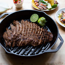 Black cast iron grill pan with dual handles and raised ridges, designed for stovetop or oven cooking.