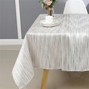 White and silver jacquard tablecloth draped over a dining table, highlighting its elegant woven texture.
