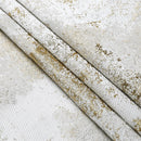 A close-up of a folded jacquard fabric napkin set in a white and gold tree pattern.