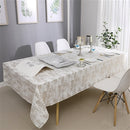 Gold mosaic jacquard tablecloth draped over a dining table set for a formal dinner with candles and place settings.