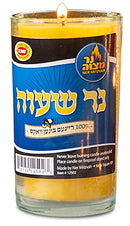 A tall, clear glass memorial candle with yellow beeswax, a burning wick, and a blue and yellow label featuring Hebrew text and the brand 'Ner Mitzvah.'