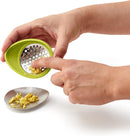 Green oval-shaped Chef'n garlic grater with a stainless steel grating surface.