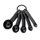 Five Black KitchenAid measuring spoon set including 1 tbsp, 1 tsp, 1/2 tsp, 1/4 tsp, and 1/8 tsp sizes.