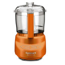 A compact orange food processor with a clear bowl and stainless steel blade shown on a white background.