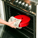A round, red stoneware tortilla warmer with a ribbed texture, a matching lid, and a small round knob handle.
